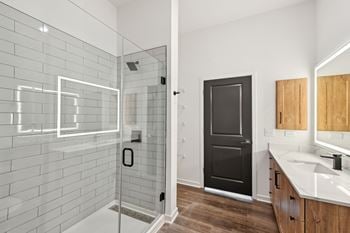 A bathroom with a black door, a glass shower enclosure, and a white sink.